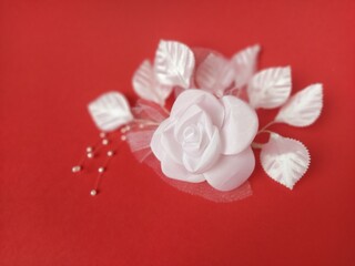 A stunning white rose stands out beautifully against a rich red background, complemented by soft leaves and small pearl accents, ideal for a wedding setting