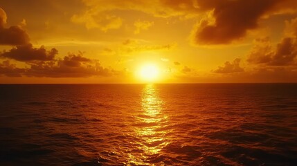 Fototapeta premium A vibrant sunset over the ocean with a golden sky and reflecting light.
