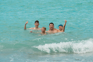 Father and sons swim in the turquoise sea