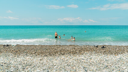 People swim in the beautiful turquoise sea in the hot summer