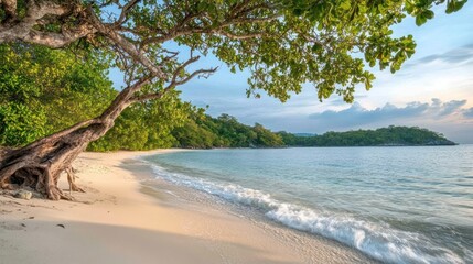 A scenic beach with clear blue water, white sand, and lush greenery. The sun is setting behind the hills in the distance, creating a beautiful and peaceful atmosphere.