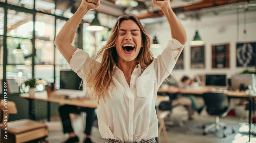 Wall mural joyful young woman celebrating success in modern workspace