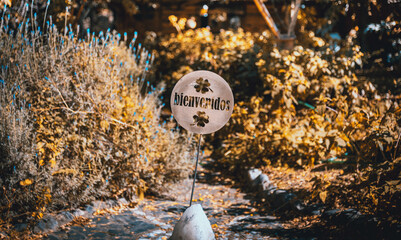 Rusty old carved welcome sign with shamrocks and a soft blurred de-focused yellow foliage background in spanish