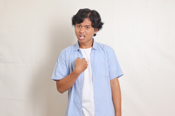 Portrait of upset Asian man in blue shirt direct finger own chest listen unfair blaming, saying...