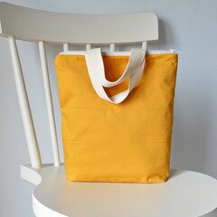 Mustard yellow zipper bag and white wooden chair