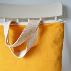 Mustard yellow zipper bag and white wooden chair