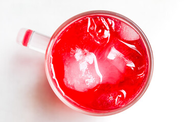 a glass of red fizzy drink with ice cubes