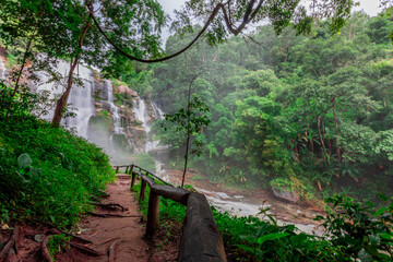 Natural blurred background of waterfalls, fast-flowing currents and water droplets from the wind blowing among the rocks and surrounded by big trees, spontaneous beauty