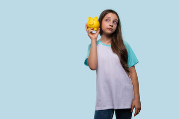 A young girl holds a yellow piggy bank