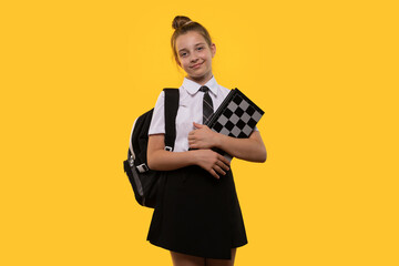 Schoolgirl poses with chessboard, showing readiness to play.