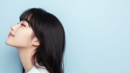 Naklejka premium Stunning Korean girl in white, with long black hair and soft bangs, profile shot against light blue background.