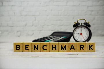 Benchmark with wooden blocks alphabet letters and calculator, alarm clock on