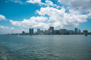 Obraz premium A picturesque view of a city skyline with vast water in the foreground under a blue sky with scattered clouds.