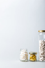 Organic dietary supplements, many capsules of vitamins and minerals in small glass jars on grey background. Nutritional supplements, pills and tablets. Healthy lifestyle.