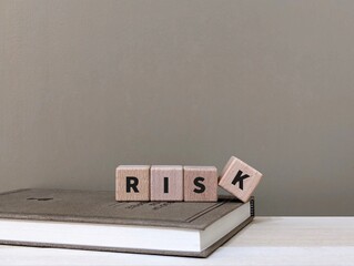 a stack of wooden blocks on book with the word risk on them. business finance