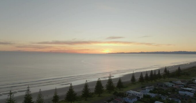 Flying towards the beautiful sunrise over Ohope Beach, Whakatane, New Zealand