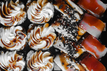 Delicious assortment of sushi rolls and desserts arranged elegantly on a black platter