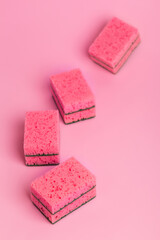 Pink kitchen sponges for washing dishes on a pink background, top view. Homework. Household work. Washing dishes.