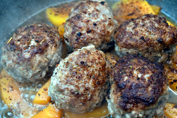 Clouds of steam rise from the meat patties cooking in a frying pan.