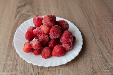 White Ceramic Saucer with Frosted Frozen Strawberries on Brown Wooden Surface, Matte and Neutral Composition
