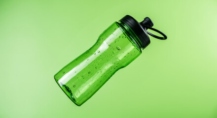 Fototapeta premium Green water bottle on vibrant background with copy space for hydration and fitness themes