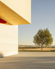 A serene landscape featuring a modern building and a solitary tree in the countryside at sunset