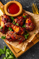 Spicy chicken wings with sriracha sauce and lime on dark background vertical photo