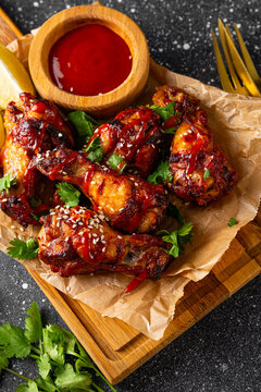 Spicy chicken wings with sriracha sauce and lime on dark background vertical photo