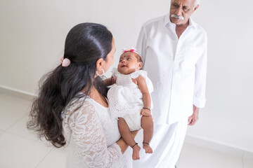 ndian family spending time together, wearing traditional and casual outfits with a baby, a young girl, and grandparents in a high-rise apartment in Kuala Lumpur, Malaysia.