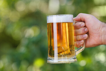 closeup male hand with mug of light beer