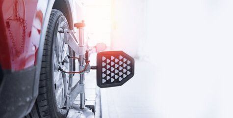 Closeup car wheel alignment on stand with sensors check in service station. Vehicle inside garage...