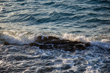Obraz premium Waves crashing over a cluster of dark rocks, turbulent ocean