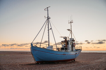 Fishing boat on Slettestrand Beach, Denmark, at sunset by the sea
