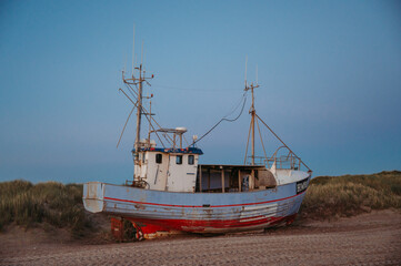 Fishing boat on Slettestrand Beach, Denmark, at sunset by the sea