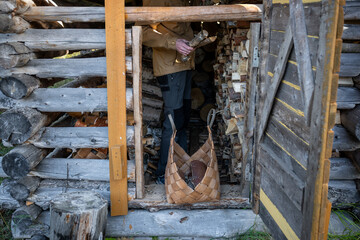 Man piling dry split firewood to basket