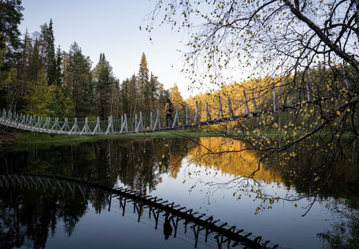 man in a yellow jacket crossing a suspension bridge in Finland