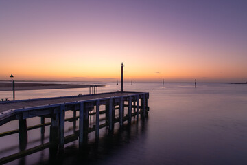 Fototapeta premium Beautiful sunrise over still ocean by wooden pier in Barwon Heads