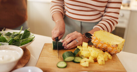 House, hands and woman cutting cucumber, healthy meal and organic food with nutrition. Wellness, people and knife with pineapple, wooden board and hobby with salad, ingredients and lunch with closeup