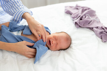 Mom change her son clothes on bed