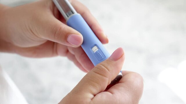 A super close up of a young woman priming the pen injector, prepering it for injection