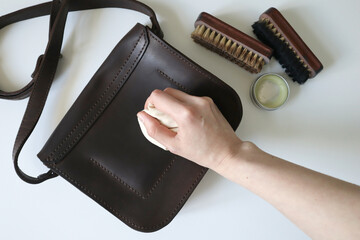 Photo process of cleaning leather products. Crazy horse leather bag. Human hand with a sponge....