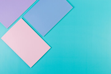 Top view of pink, purple and blue notebooks on blue background. Pink, yellow and blue pens, school, office wallpaper. Flat lay, copy space.