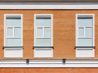 Three windows on a brick building with white trim