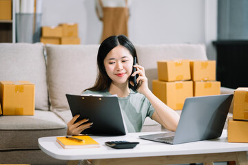 Startup small business entrepreneur or freelance using a laptop with box, checking orders from customers, woman runs an e-commerce business on websites and social media. 