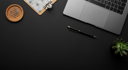 A minimalist workspace features part of a silver laptop on a sleek black surface with a pen nearby. 