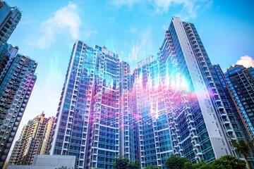 Tall glass buildings with a light blue sky background, modern architecture in a Hong Kong cityscape.