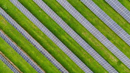 Aerial view of solar panels forming a geometric pattern on green grass
