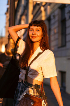A young woman walks through the city in the golden sunset light.