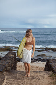 Female surfer standing with surfboard
