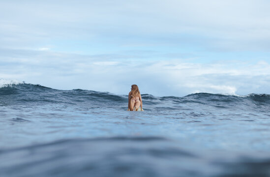 Young surfer woman going over wave